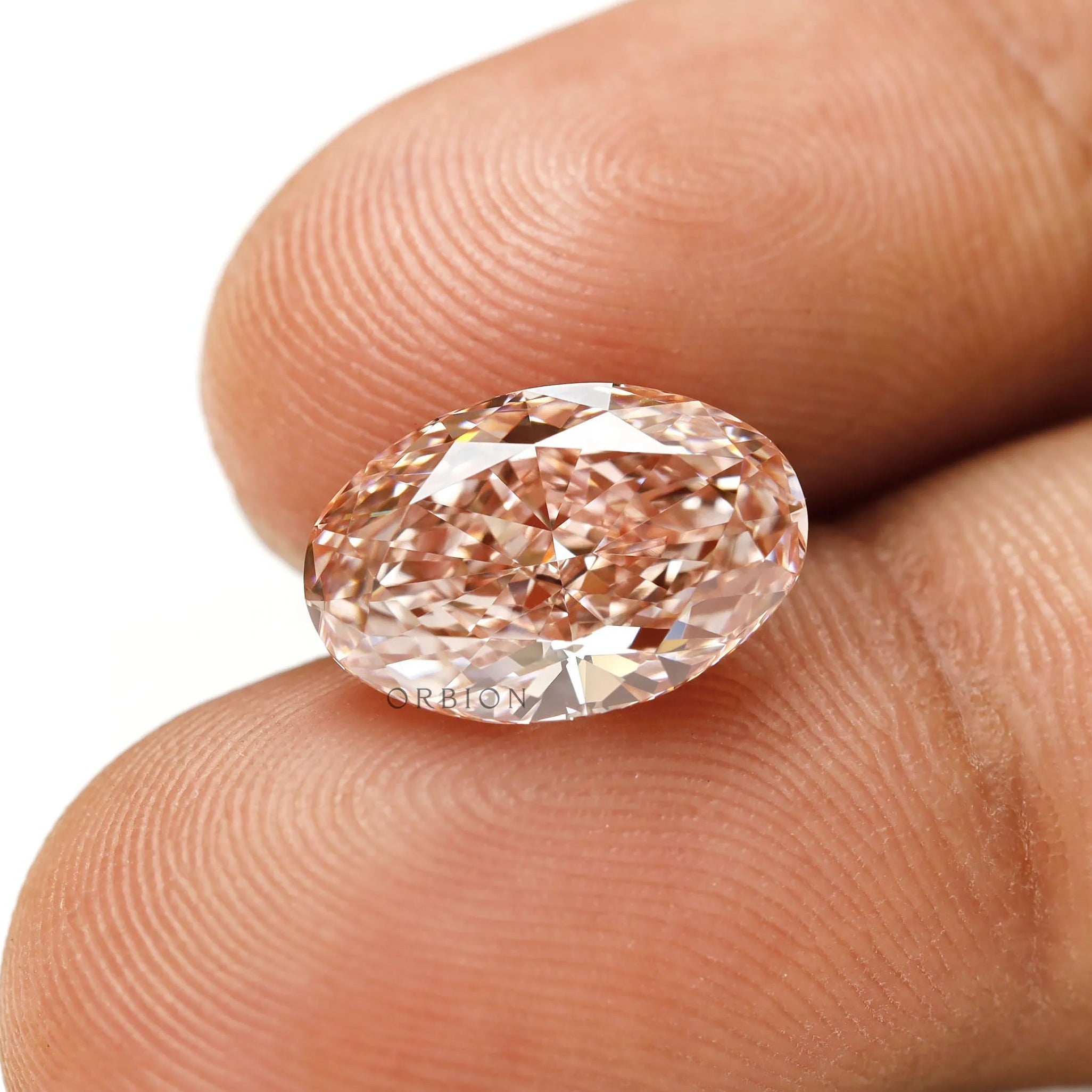 Intense pink oval lab diamond shown on fingertip closeup