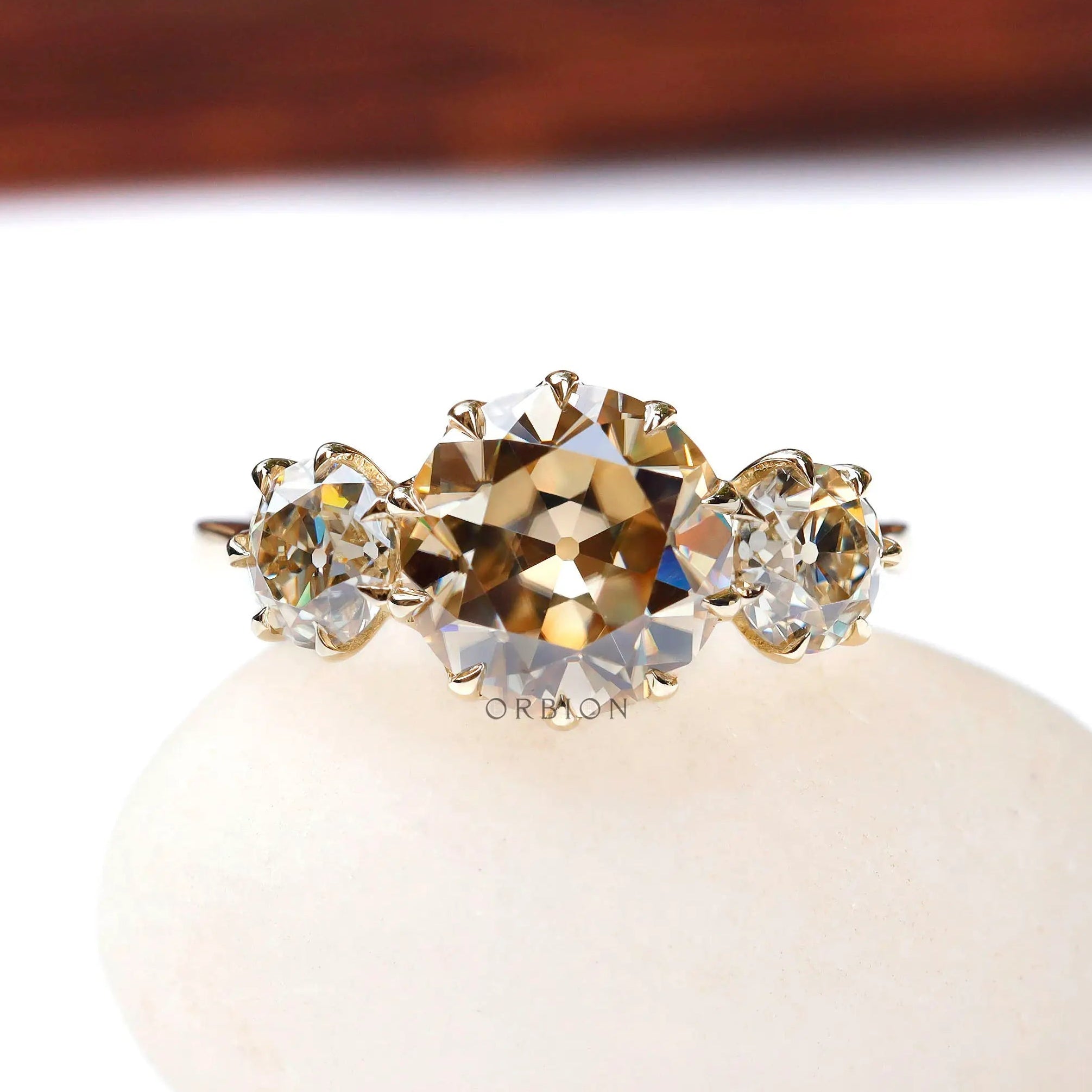 Front view champagne moissanite three stone ring on white base