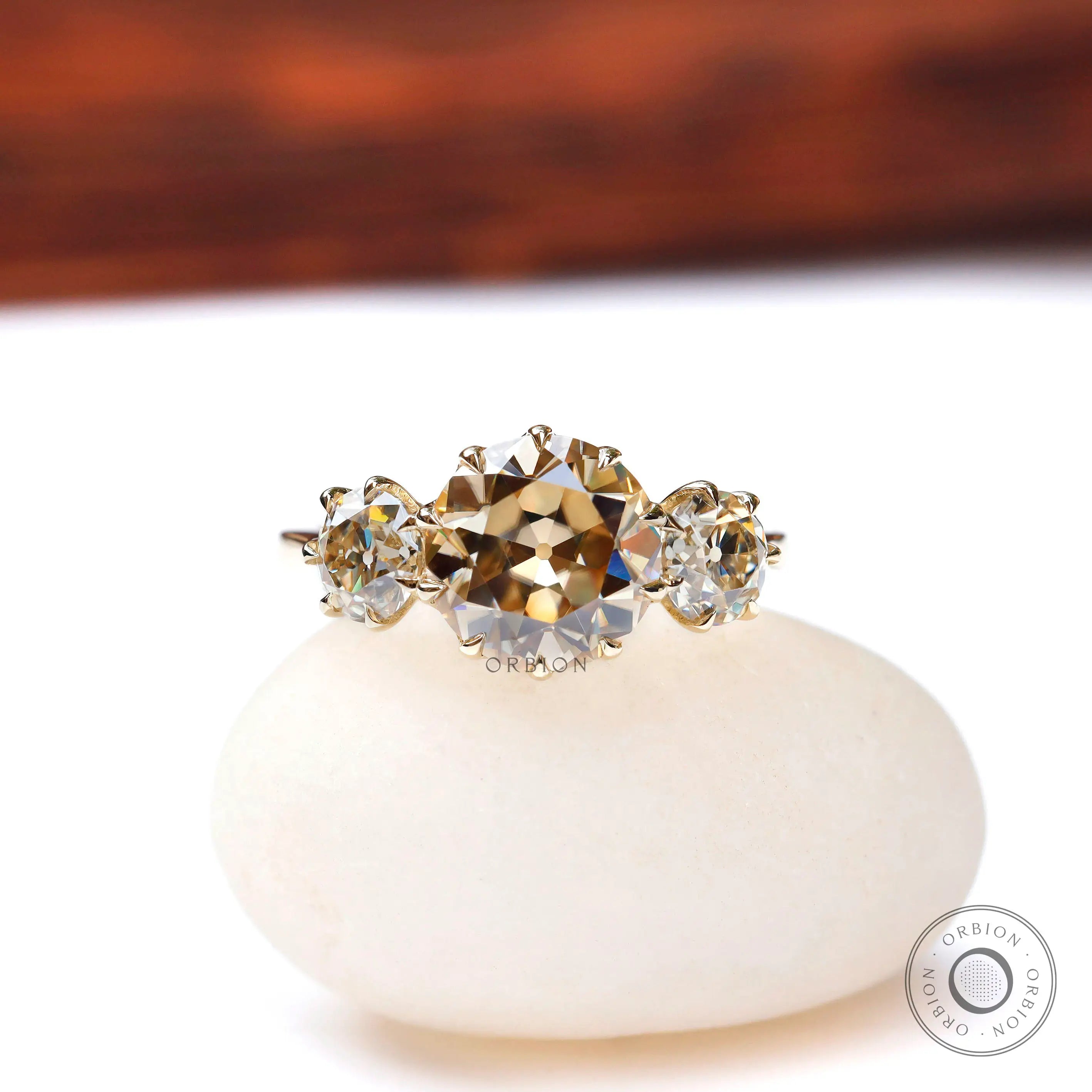 Front view champagne moissanite three stone ring on white base