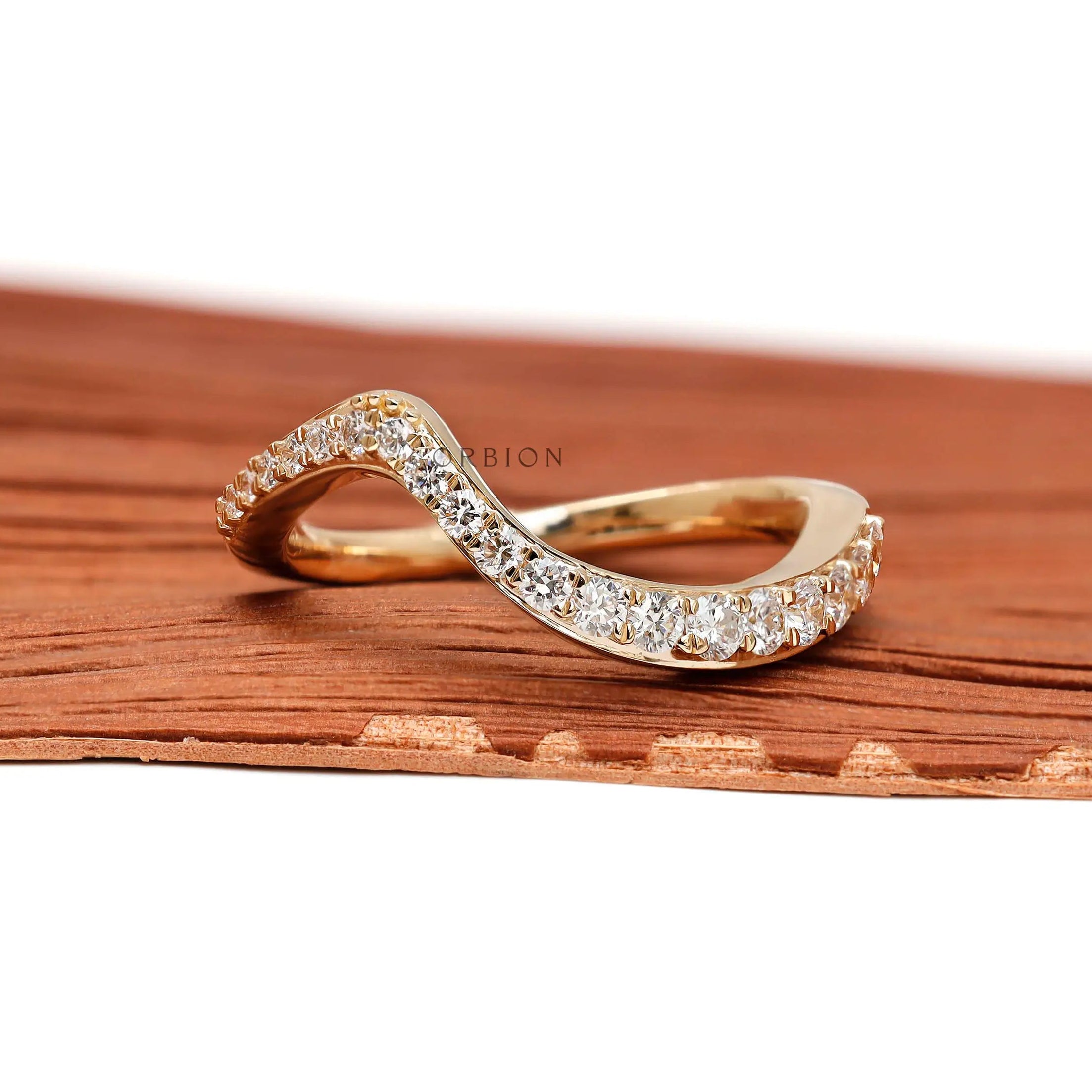 Front view of curved diamond wedding band in yellow gold