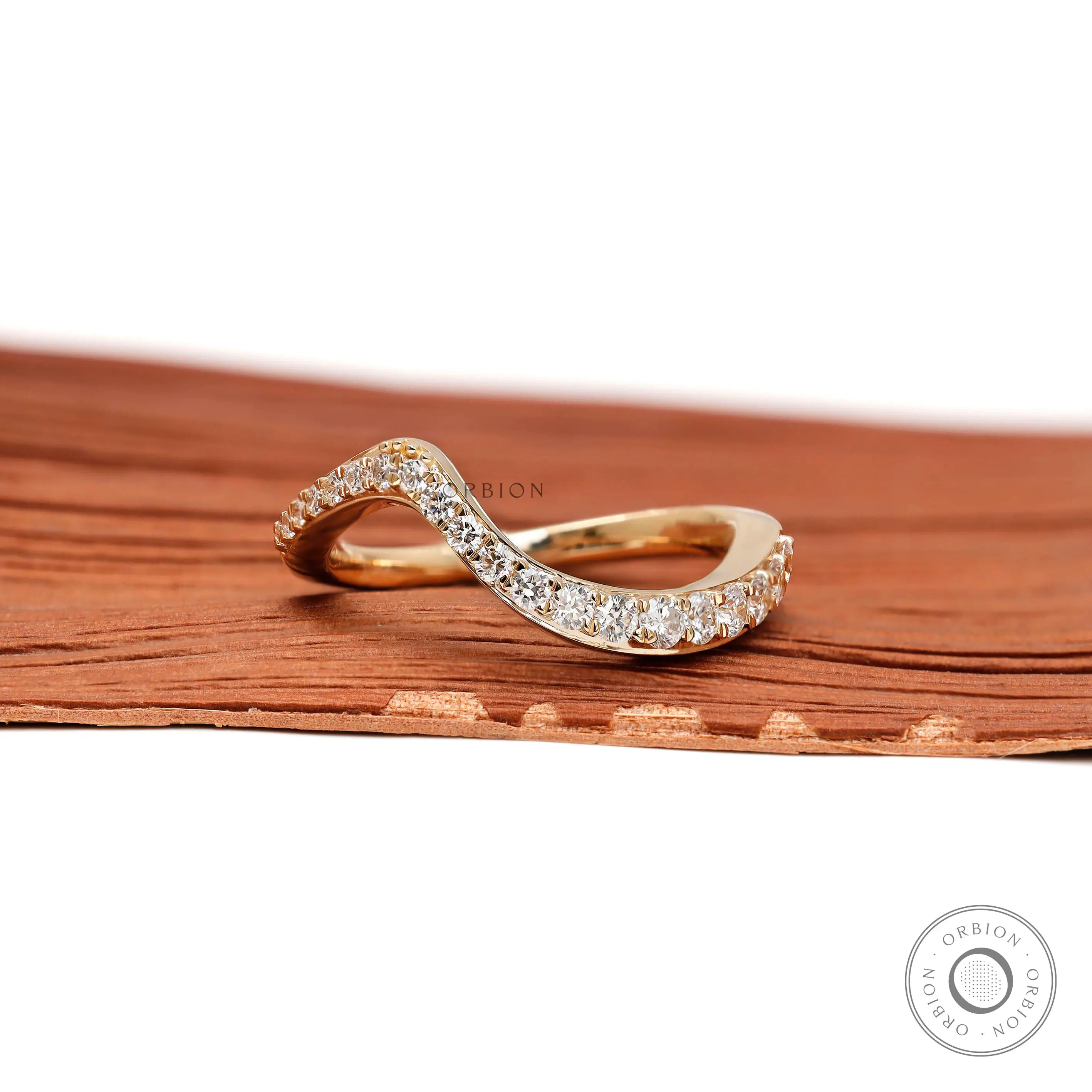 Front view of curved diamond wedding band in yellow gold