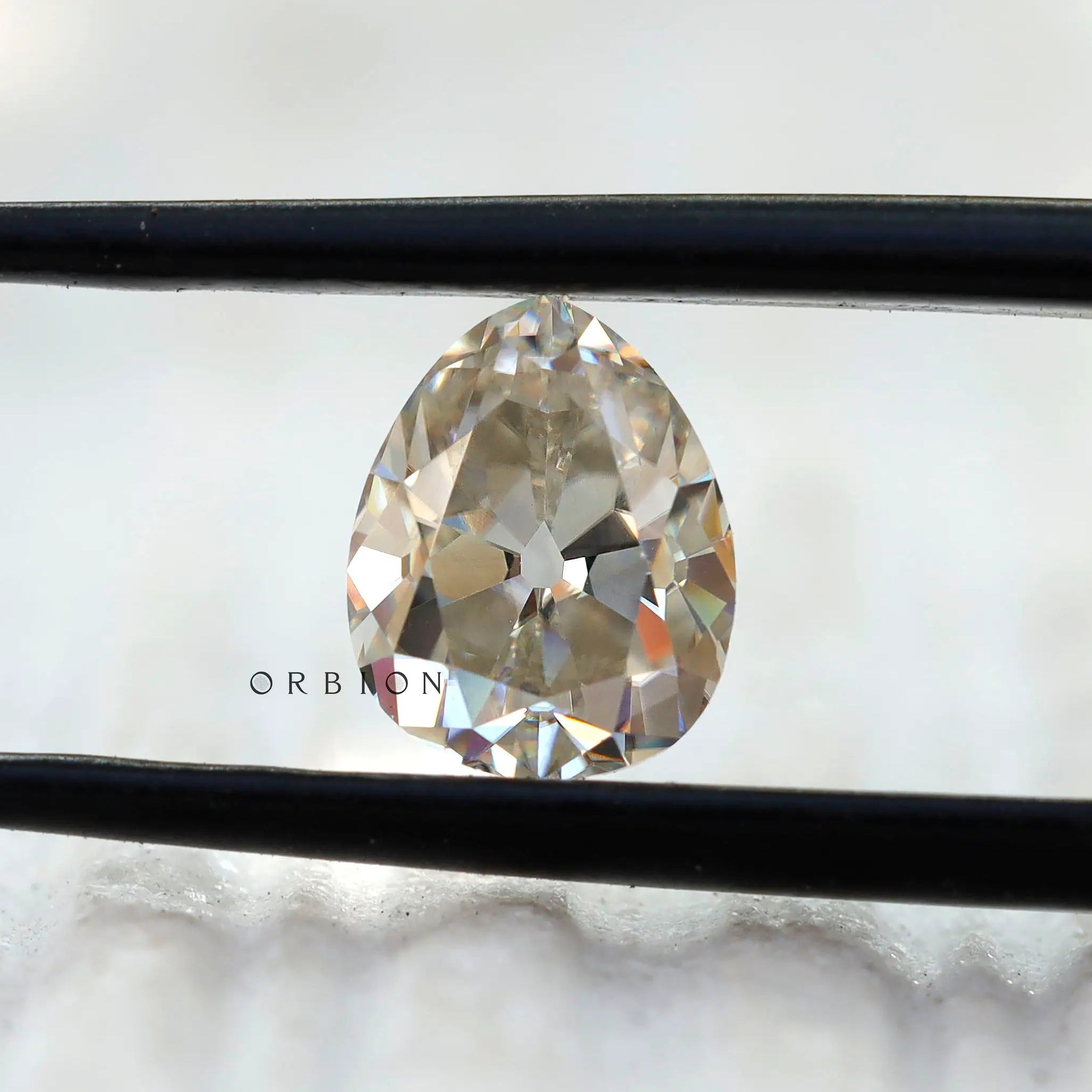 1.35 CT Old Mine Cut Off White Pear Moissanite stone in tweezers