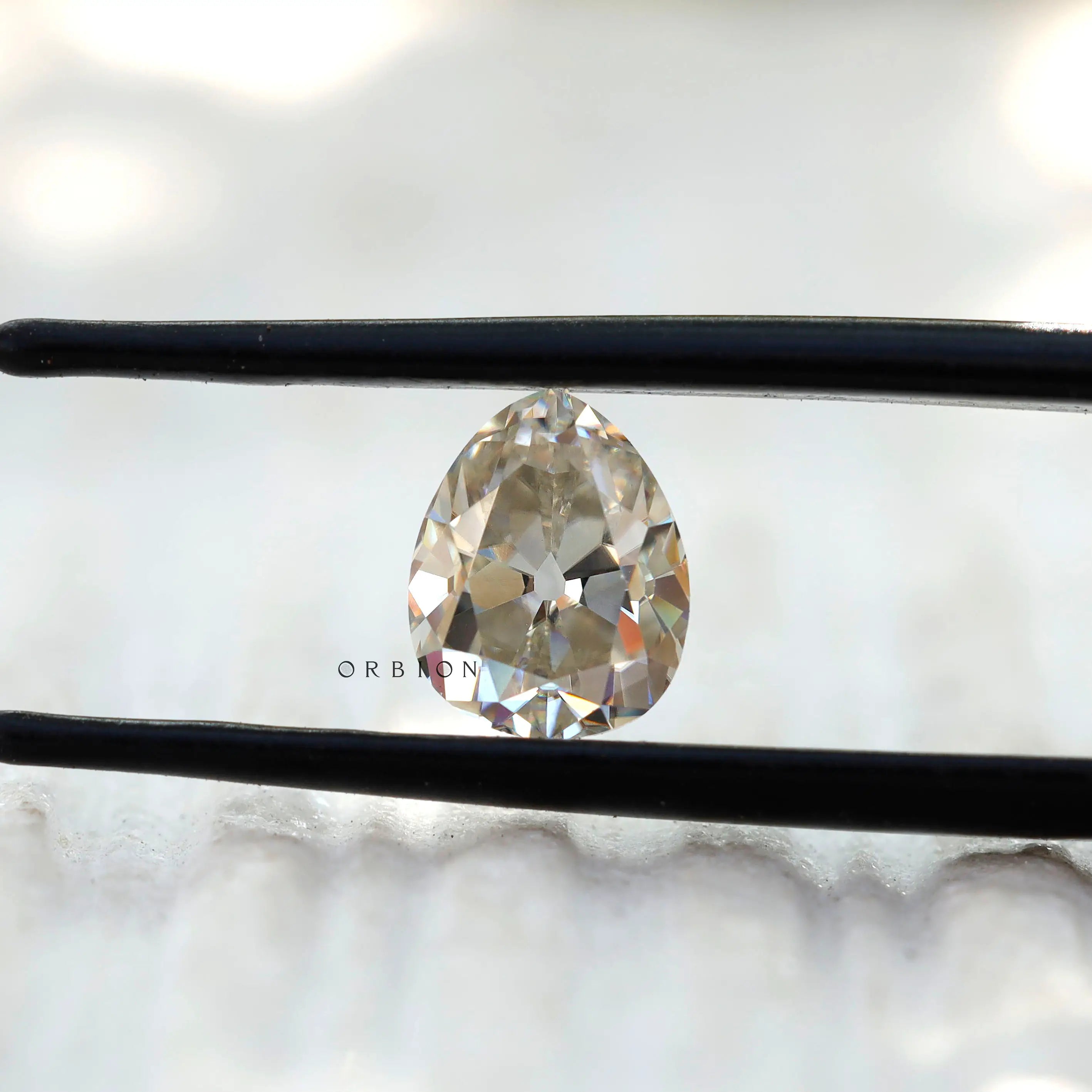1.35 CT Old Mine Cut Off White Pear Moissanite stone in tweezers