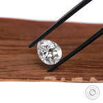 Pear brilliant cut lab diamond held above wooden surface