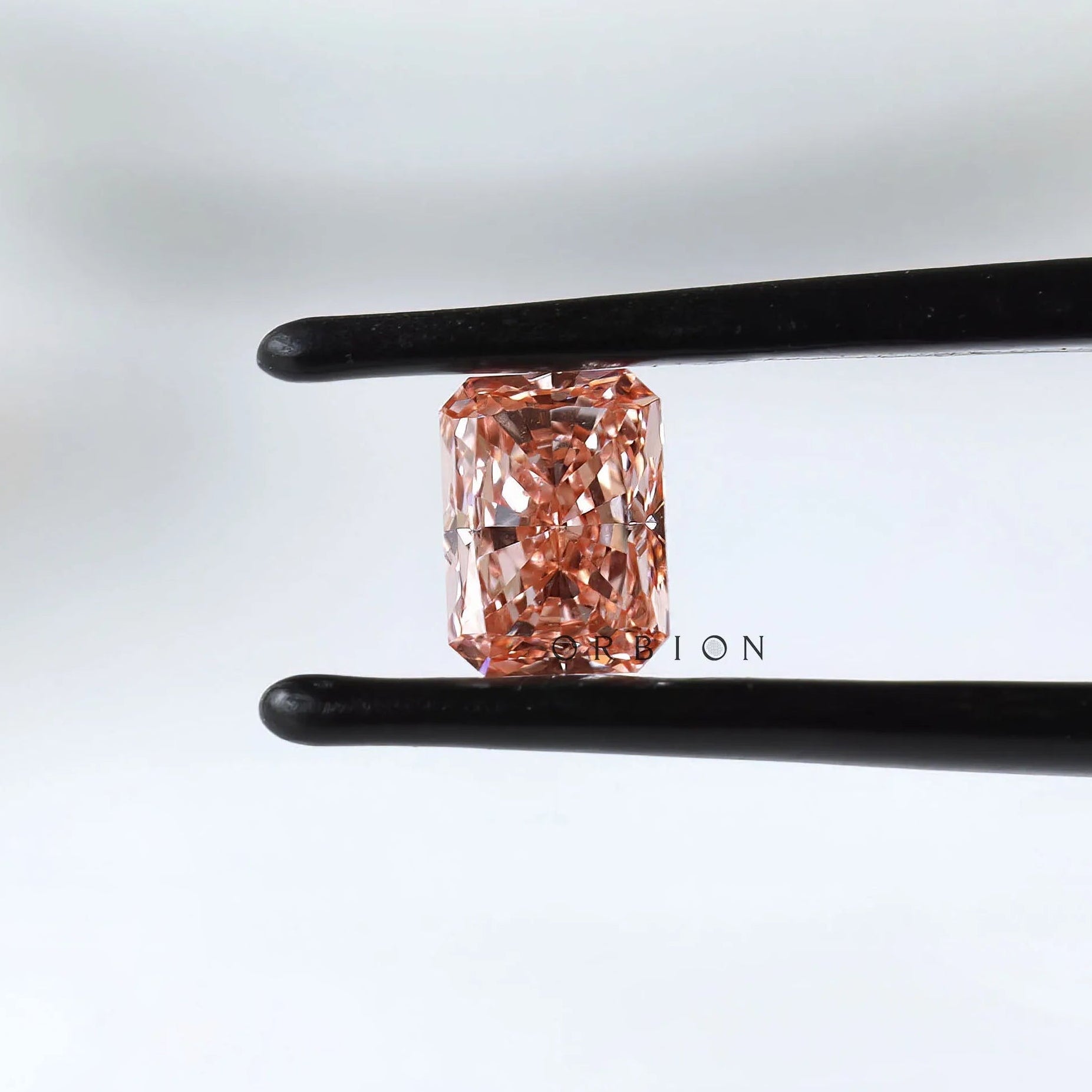 Fancy vivid pink radiant pair held in black tweezers