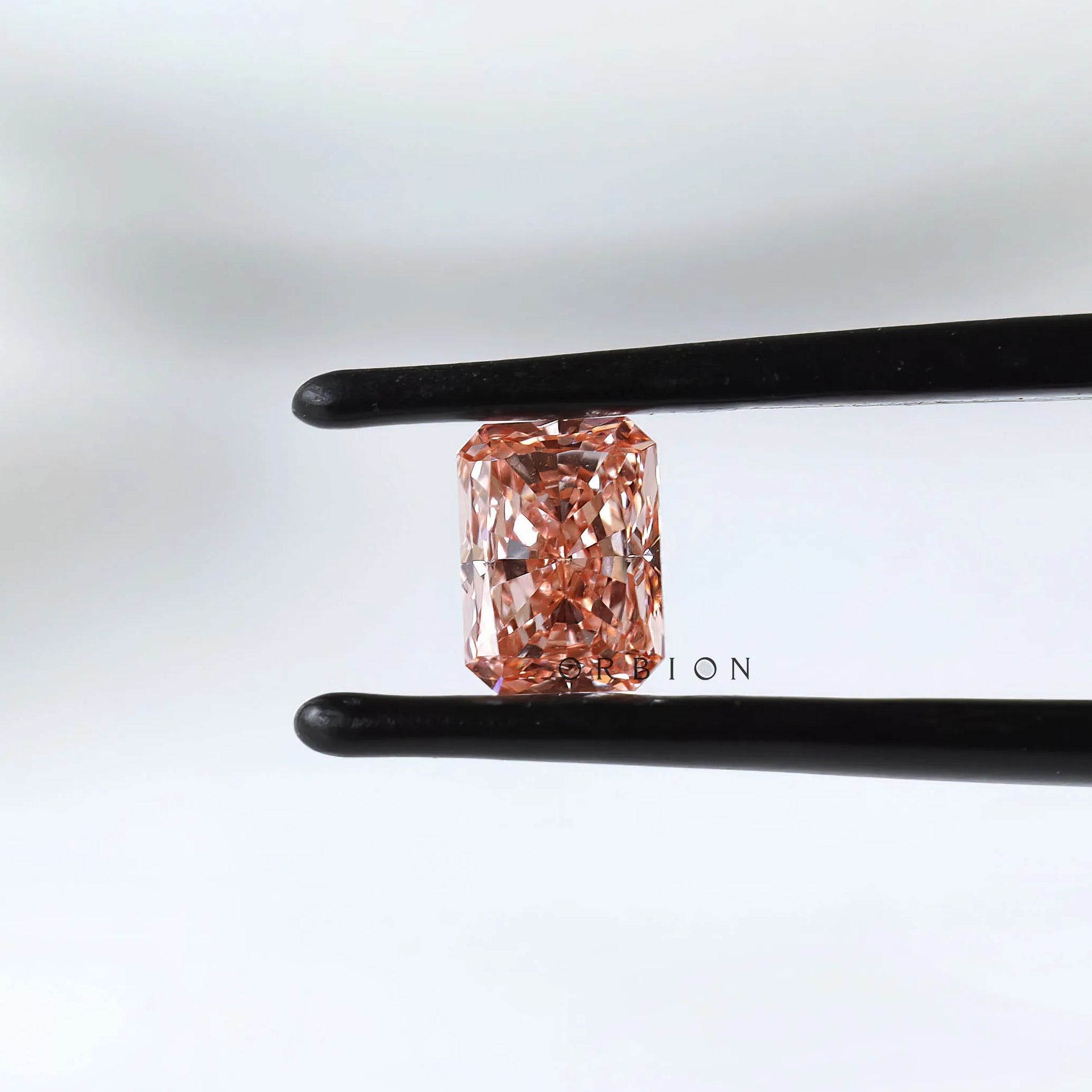 Fancy vivid pink radiant pair held in black tweezers