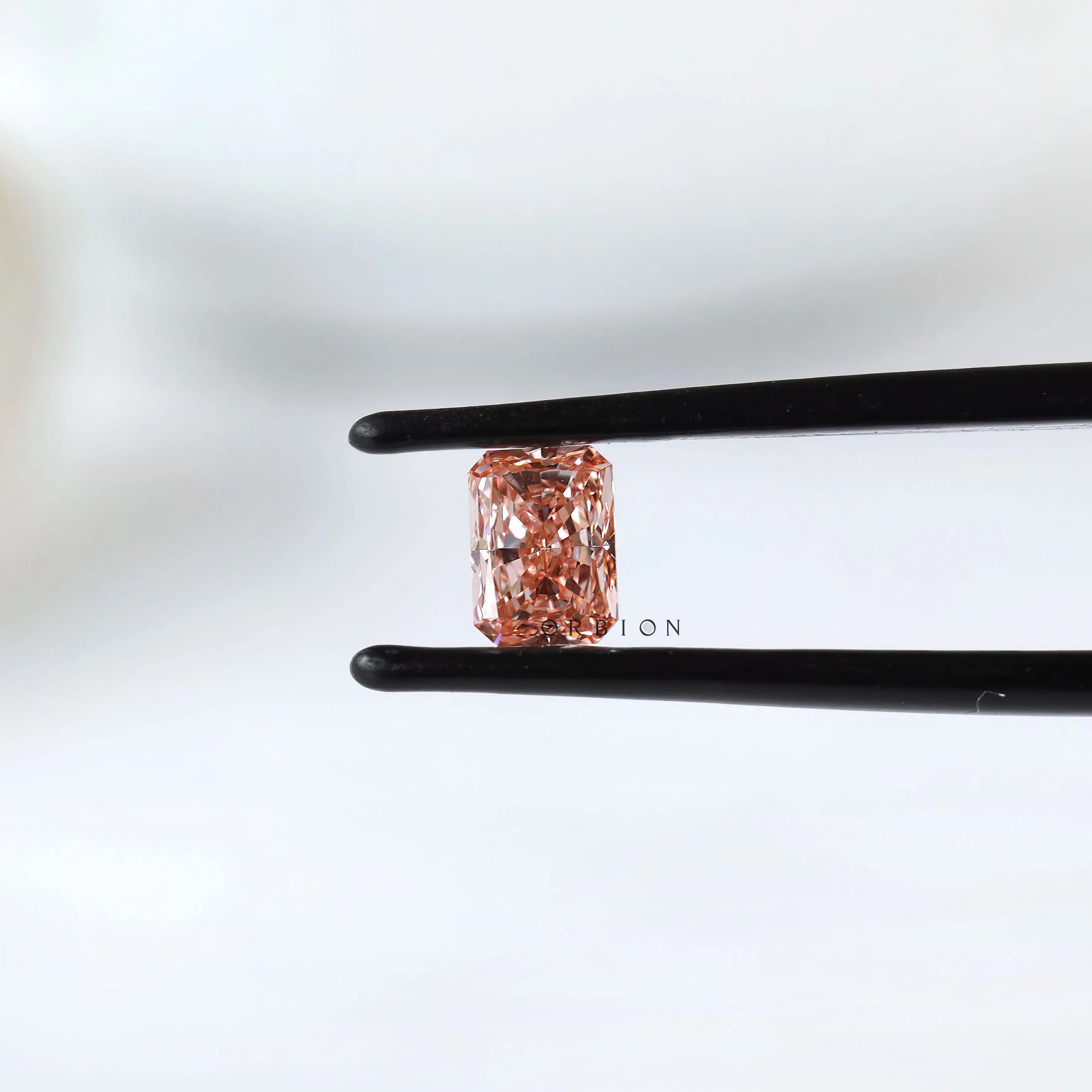 Fancy vivid pink radiant pair held in black tweezers