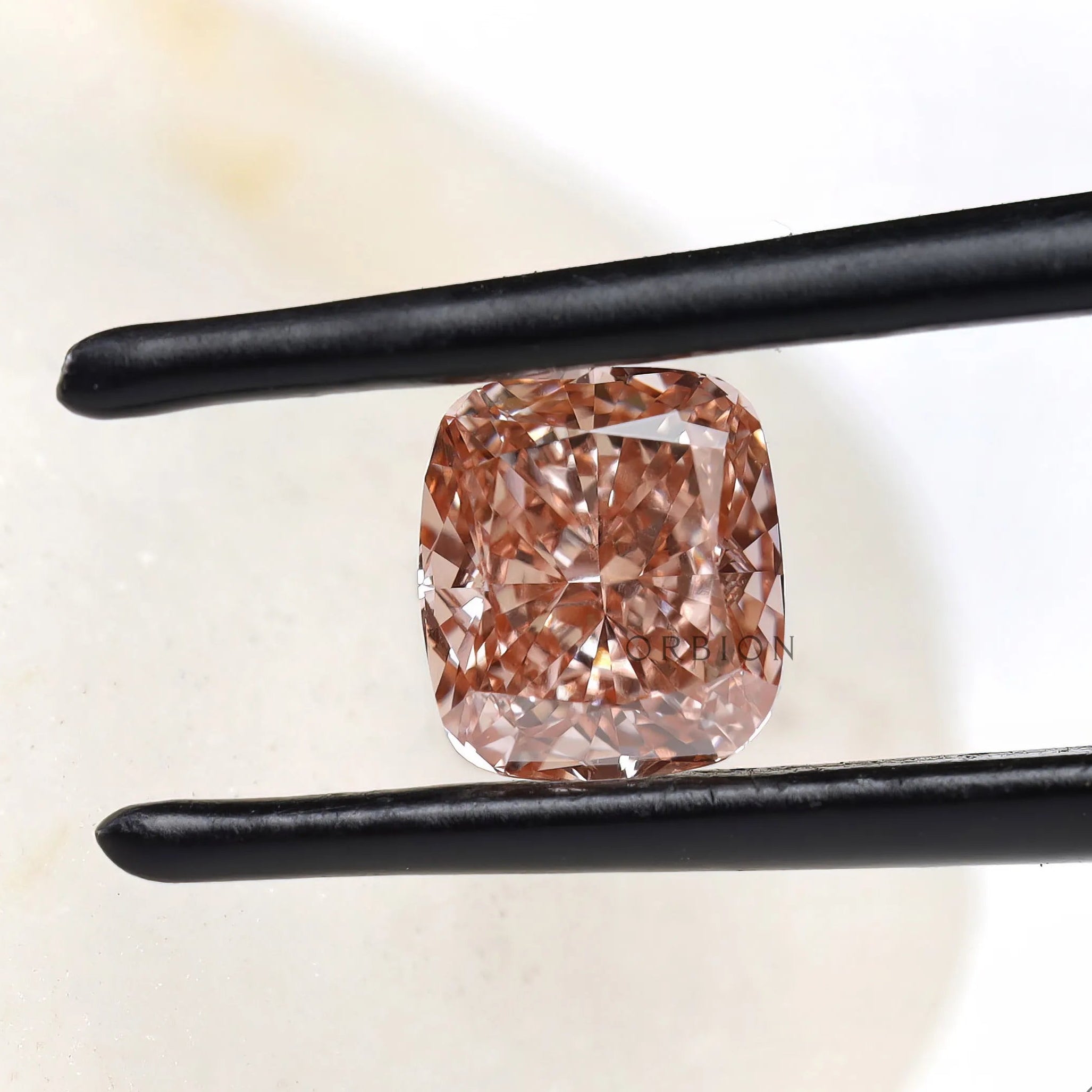 Fancy pink elongated cushion lab diamond held in black tweezers