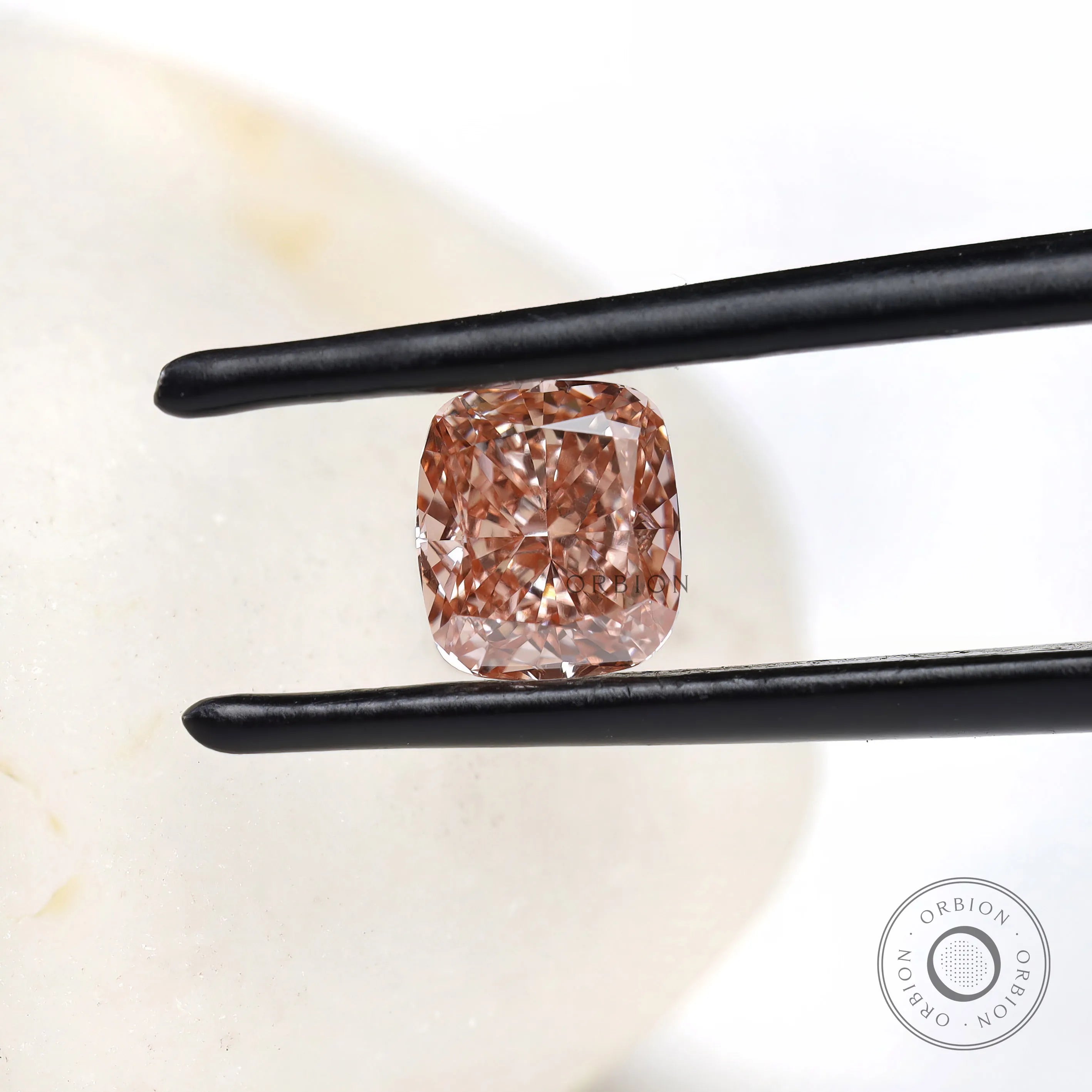 Fancy pink elongated cushion lab diamond held in black tweezers