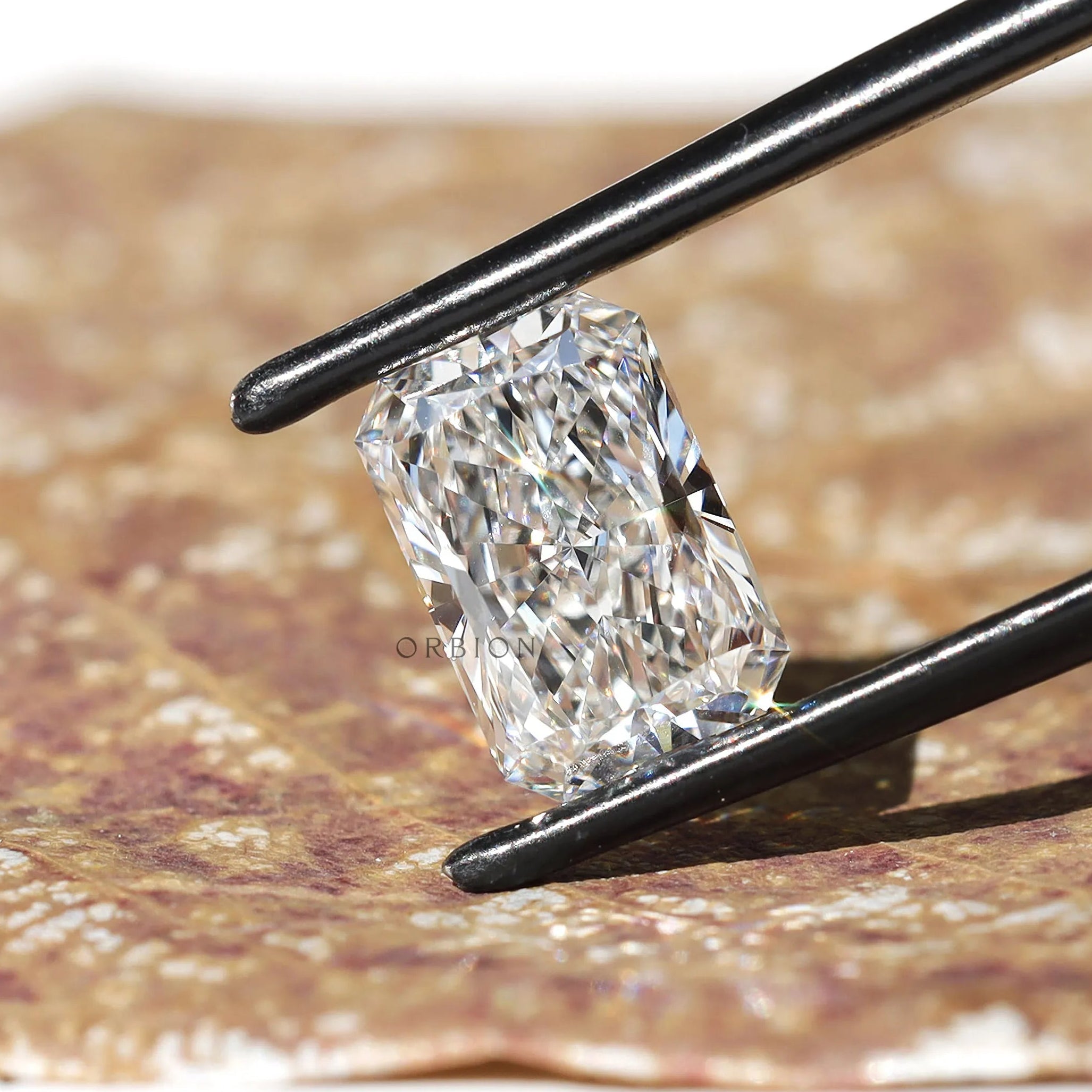 Radiant brilliant cut loose lab diamond in black tweezers