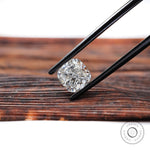 Brilliant cut cushion lab diamond held over wooden surface