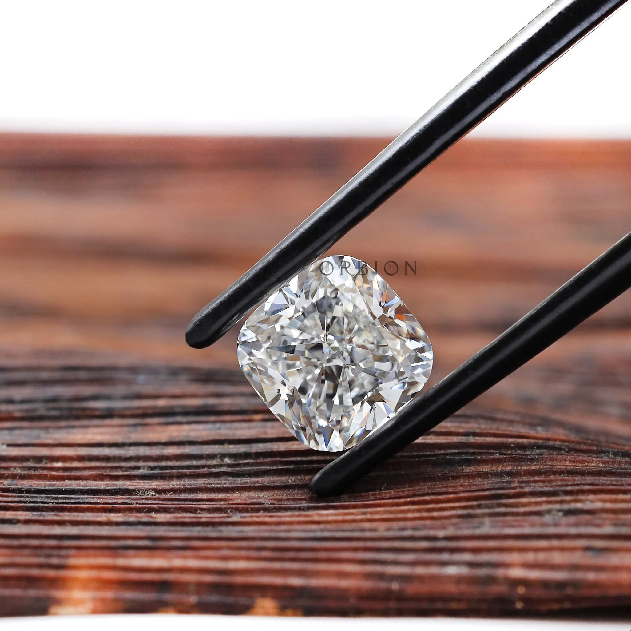 Brilliant cut cushion lab diamond held over wooden surface