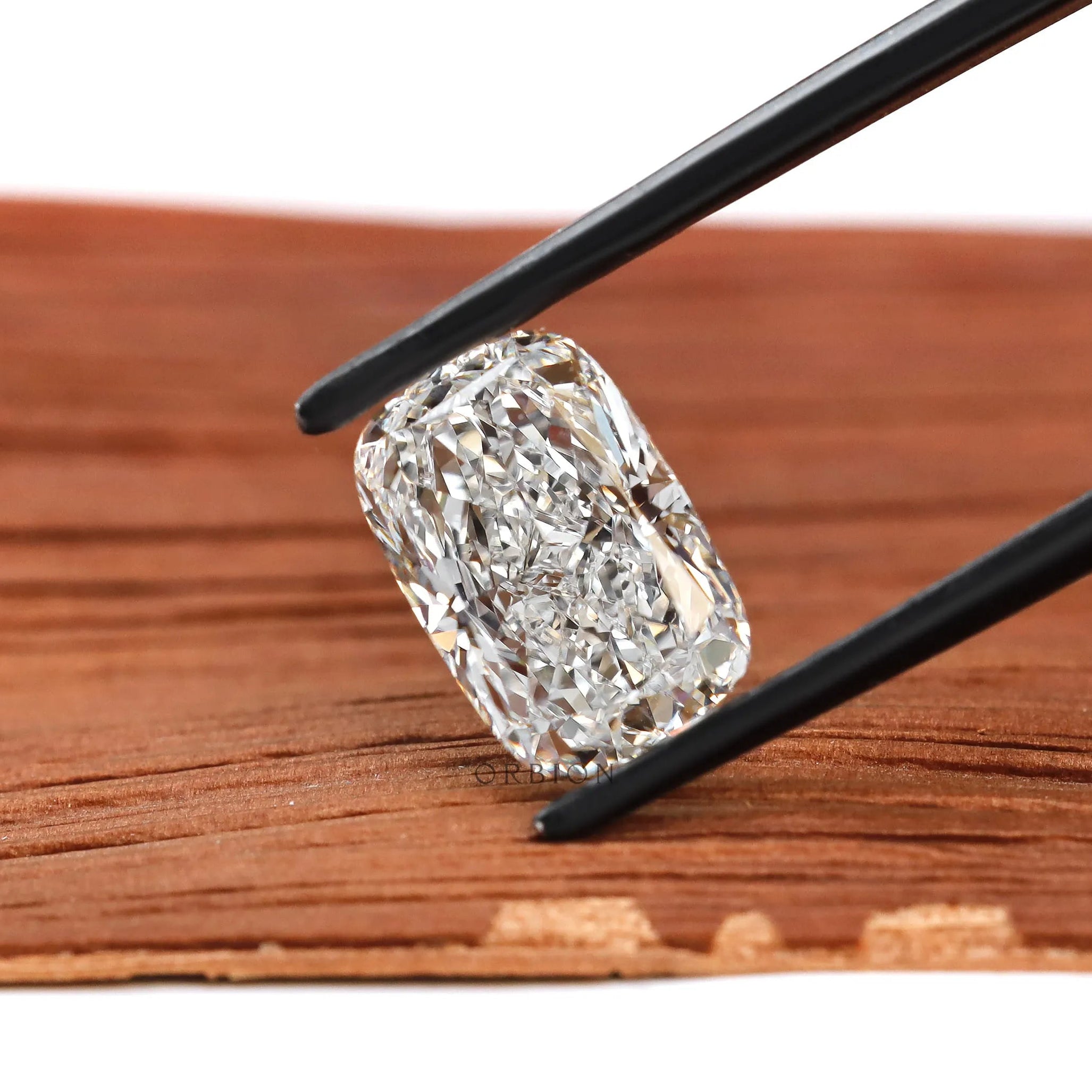 Elongated cushion crushed ice lab diamond held in black tweezers