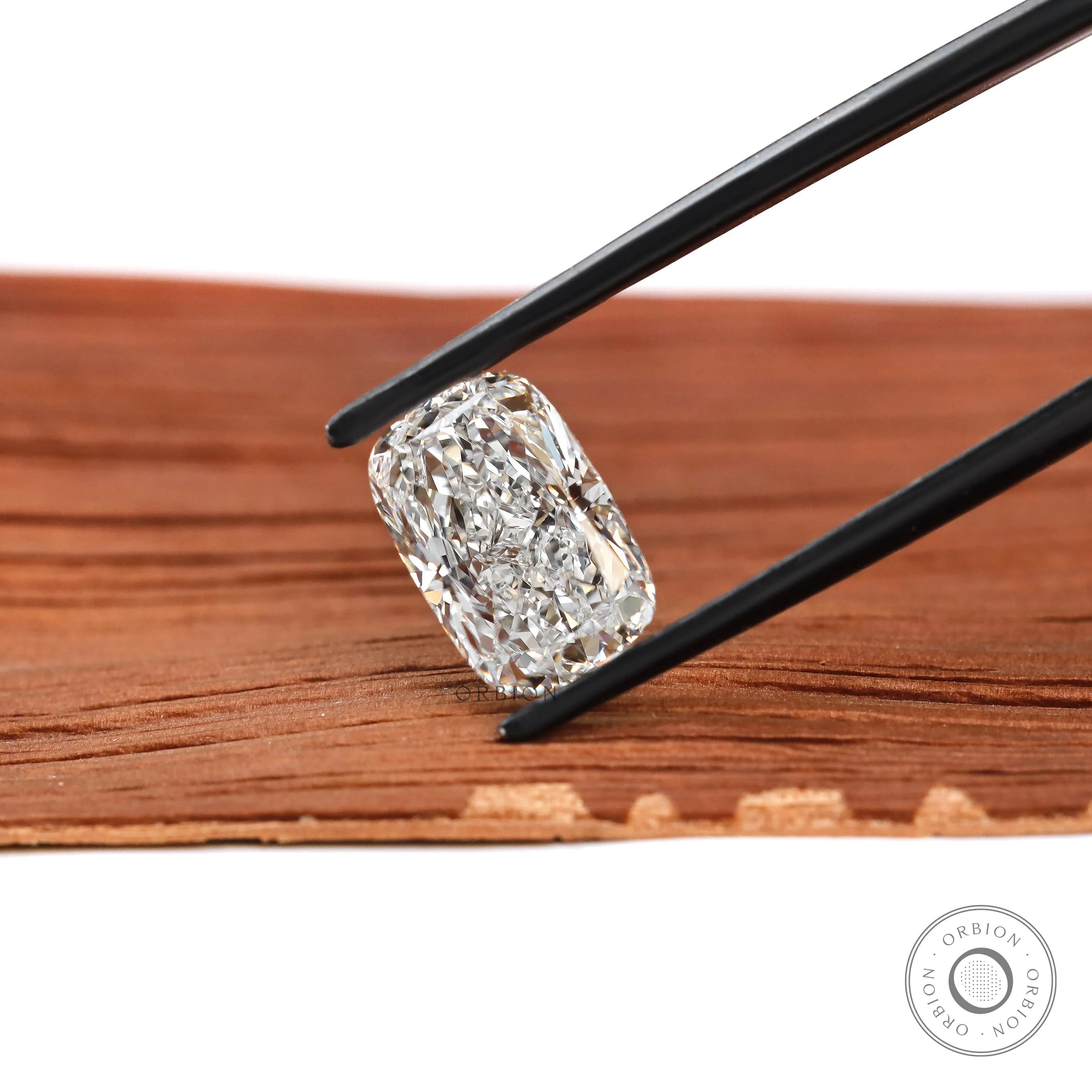 Elongated cushion crushed ice lab diamond held in black tweezers