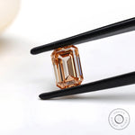 Fancy orange emerald step cut lab diamond in tweezers
