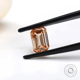 Fancy orange emerald step cut lab diamond in tweezers