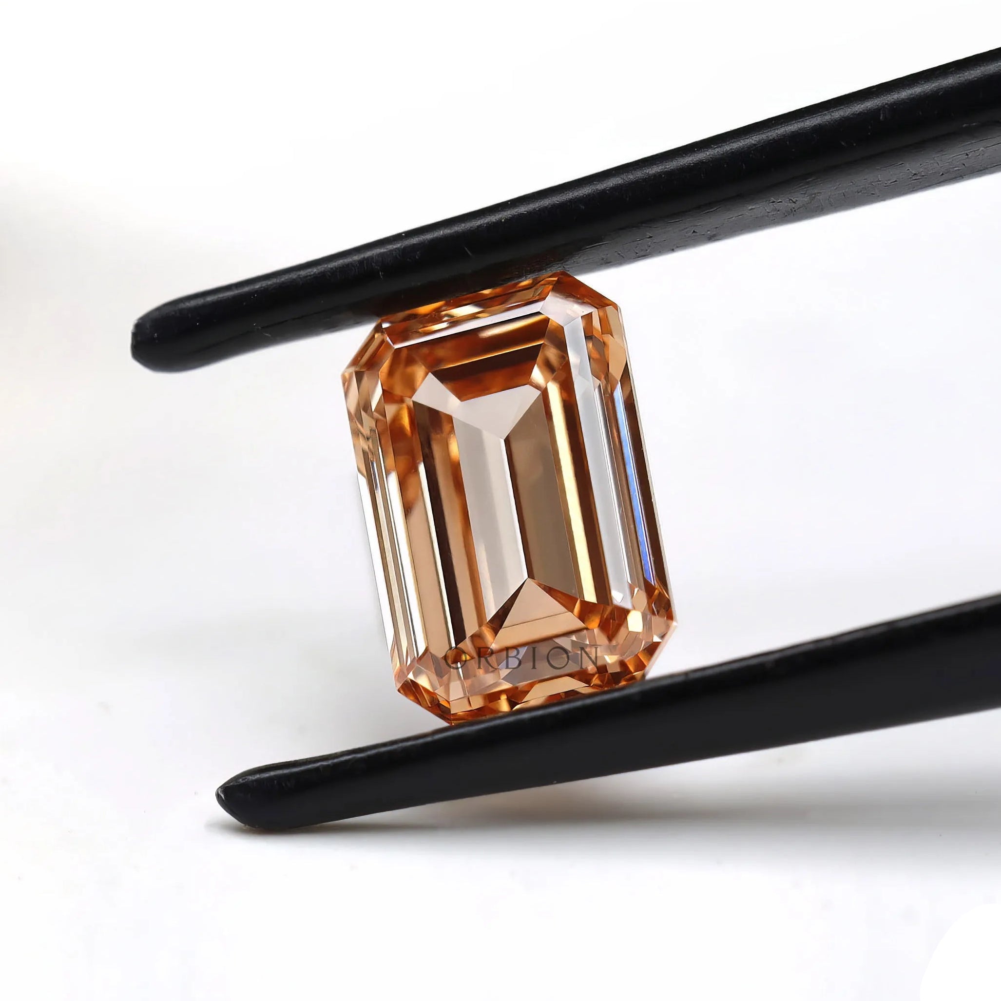 Fancy orange emerald step cut lab diamond in tweezers