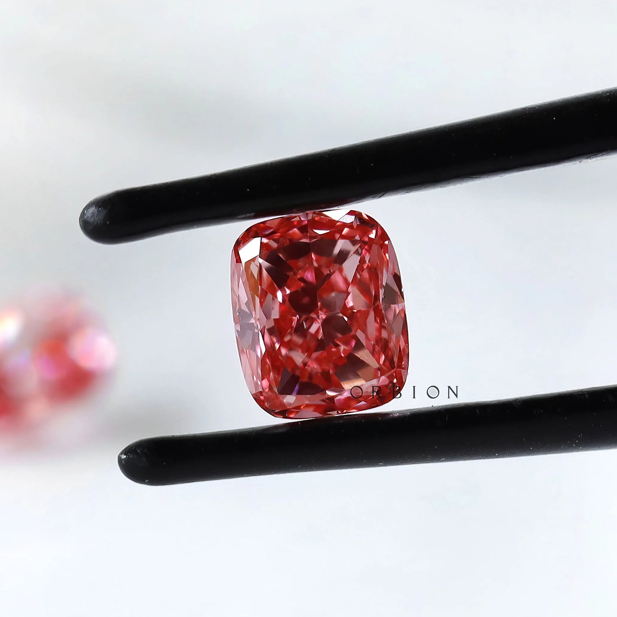 Fancy vivid pink cushion lab diamond pair in black tweezers