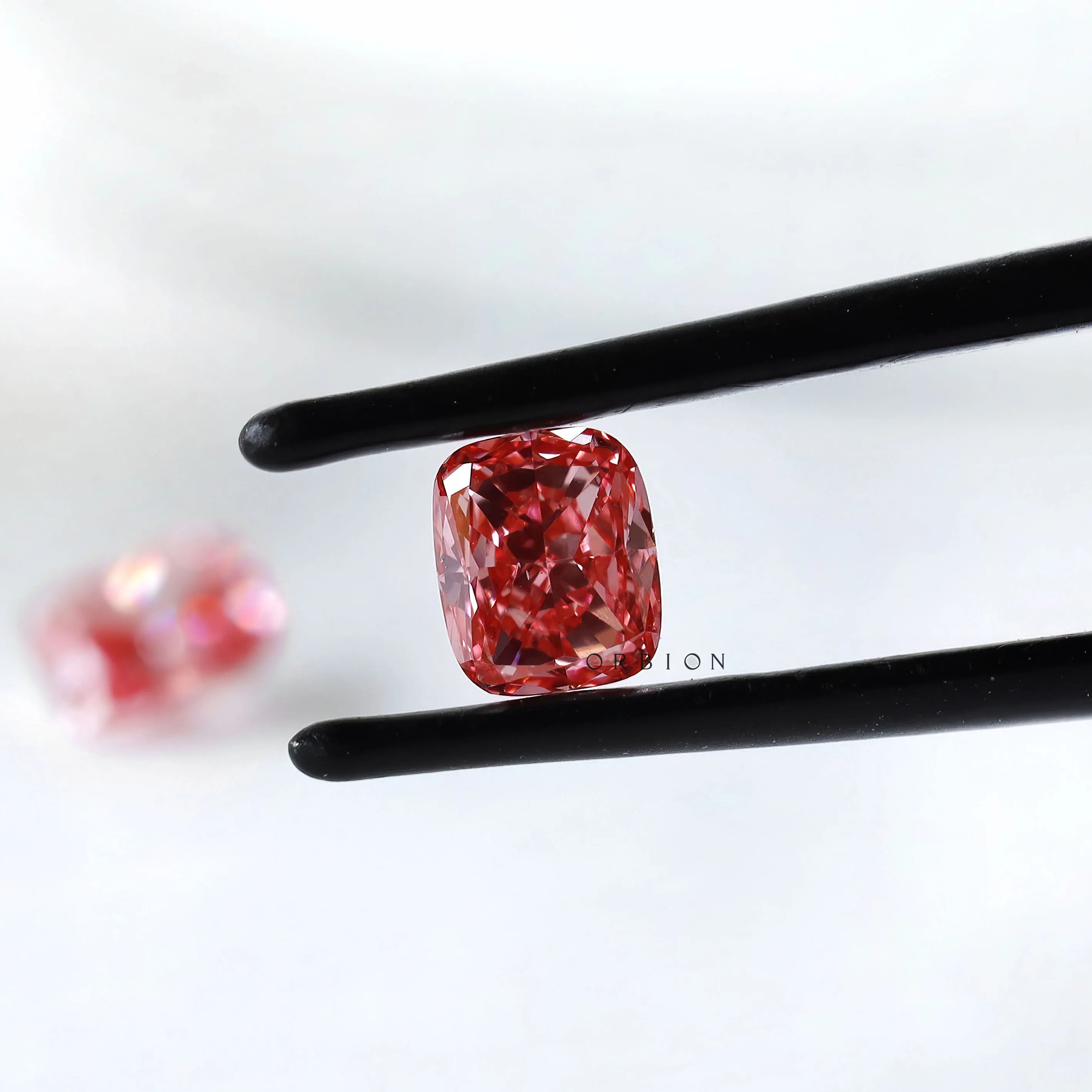 Fancy vivid pink cushion lab diamond pair in black tweezers