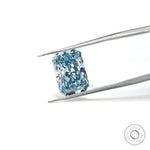 Fancy vivid blue radiant lab diamond held in silver tweezers