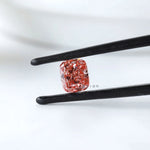 Fancy vivid pink cushion lab diamond held in black tweezers