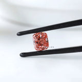 Fancy vivid pink cushion lab diamond held in black tweezers