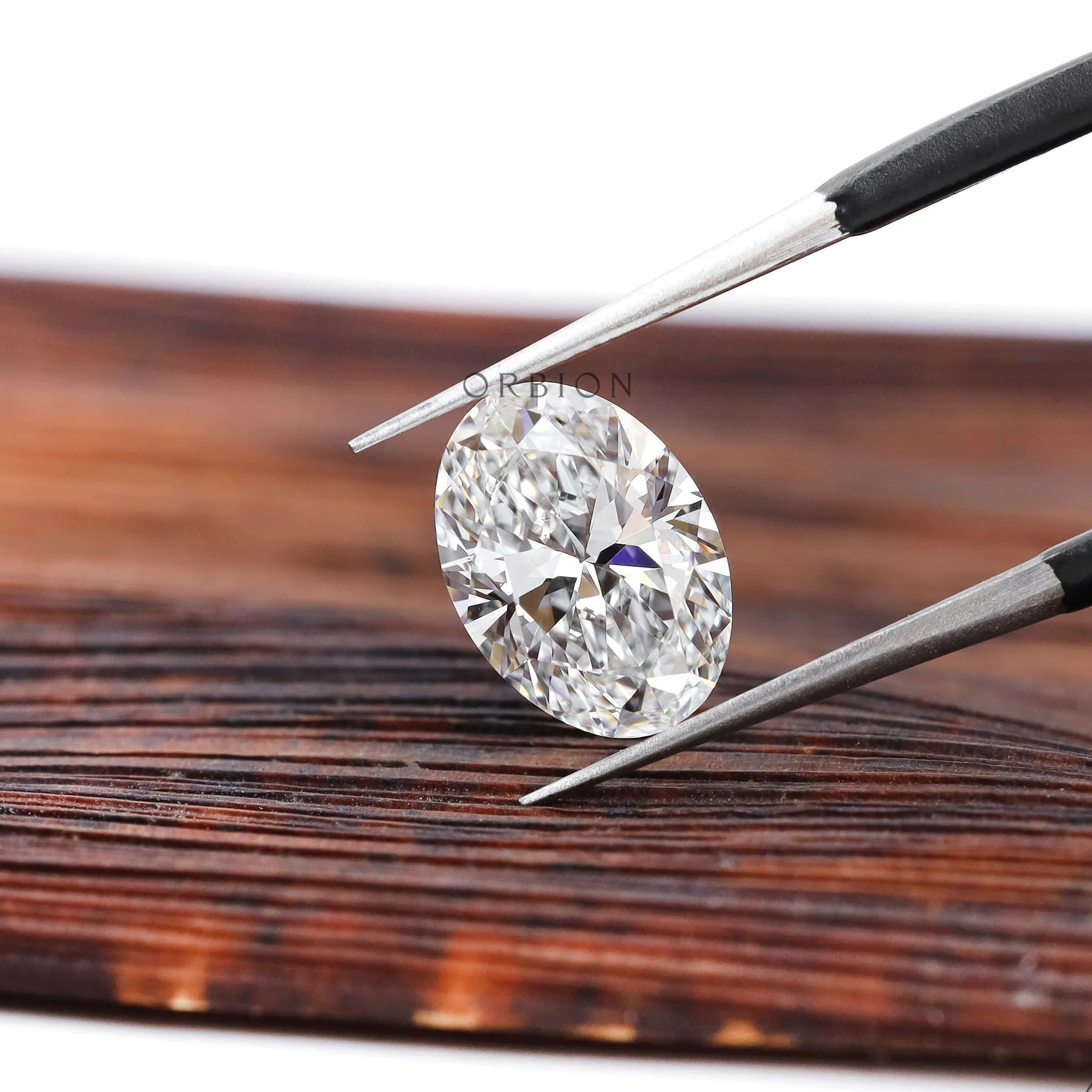 DEF oval lab diamond angled view in jeweler tweezers