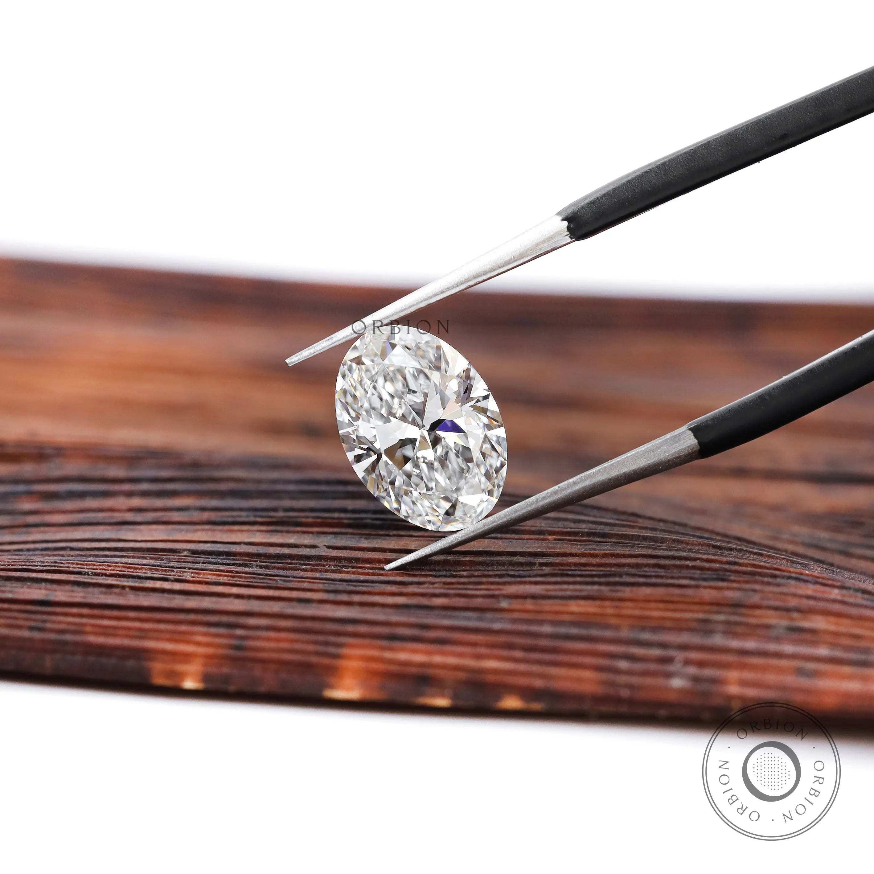 DEF oval lab diamond angled view in jeweler tweezers