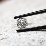 Elongated cushion old mine cut moissanite in tweezer close-up