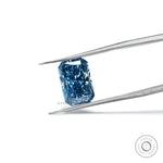 Fancy vivid blue radiant lab diamond held in silver tweezers