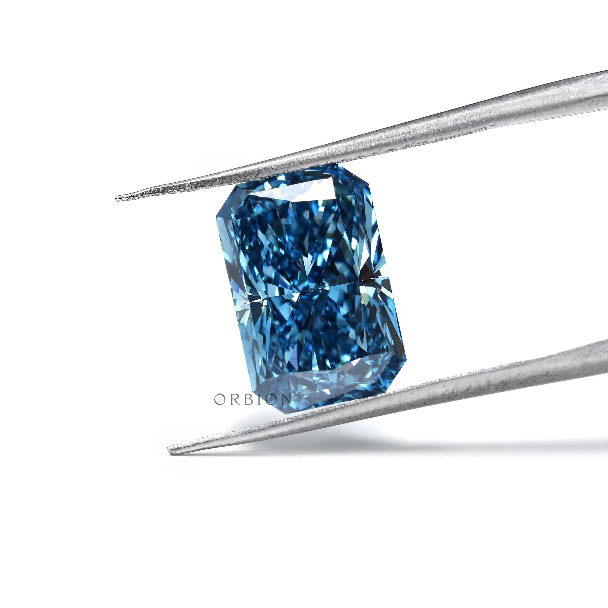 Fancy vivid blue radiant lab diamond held in silver tweezers