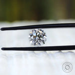 Round colorless lab diamond displayed between black tweezers