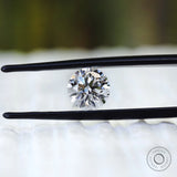 Round colorless lab diamond displayed between black tweezers