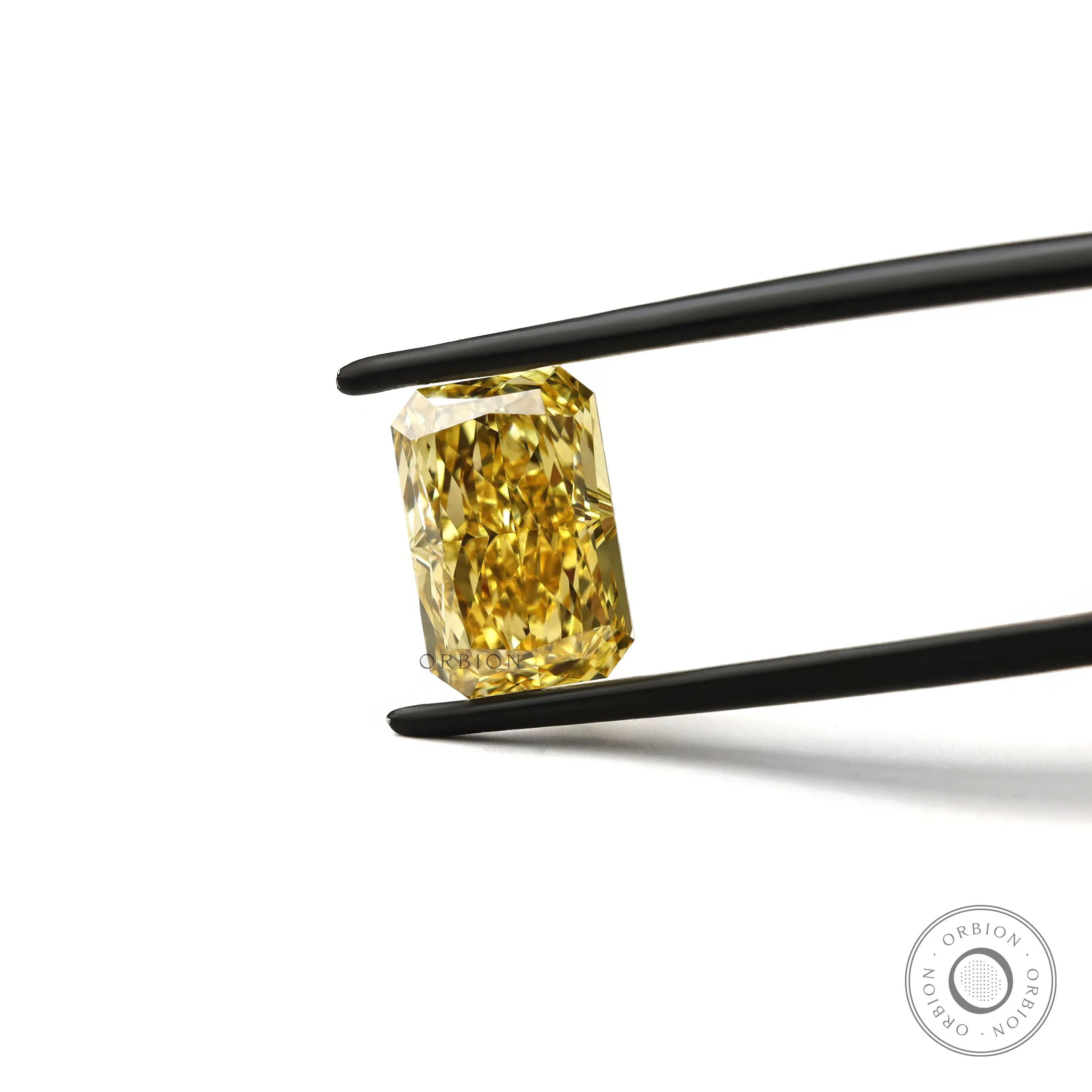 Fancy vivid yellow radiant cut lab diamond in tweezers