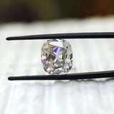 Cushion old mine cut moissanite held in tweezers