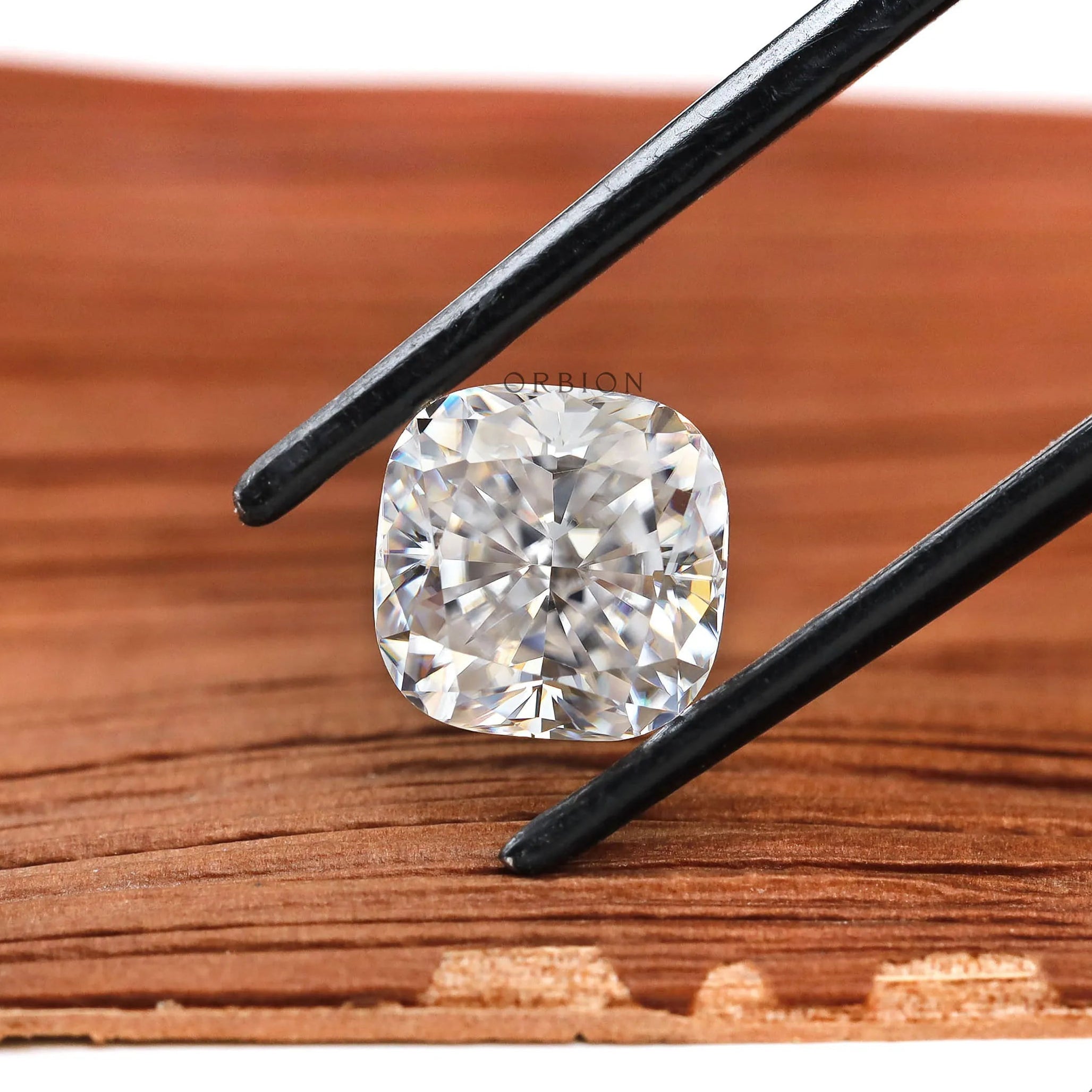 Cushion brilliant cut moissanite held above wooden surface