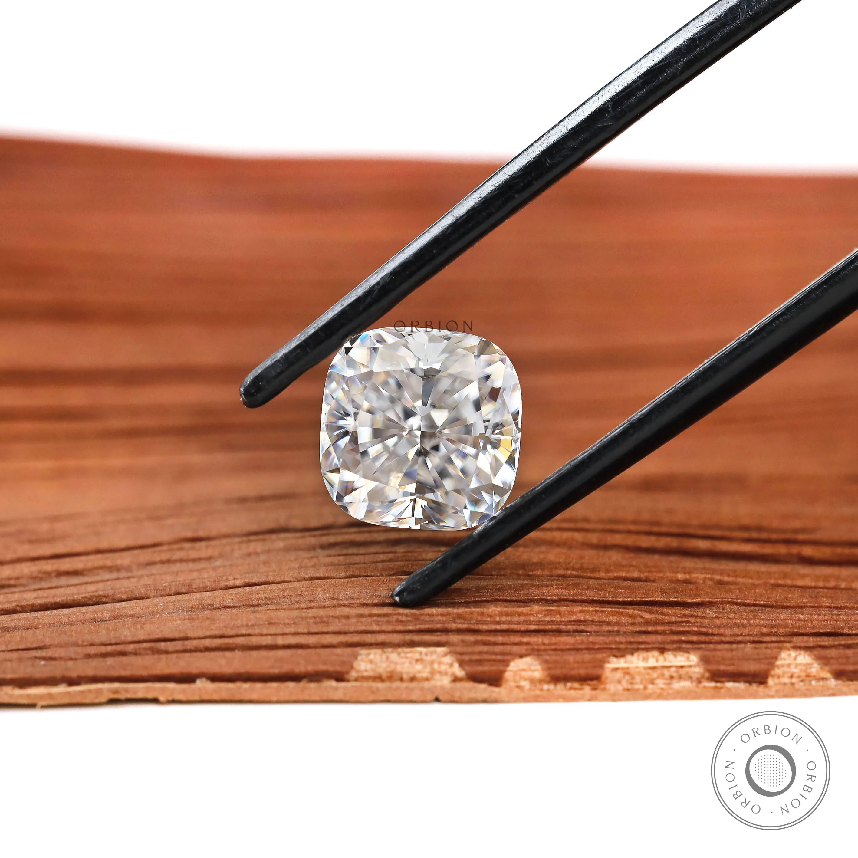 Cushion brilliant cut moissanite held above wooden surface