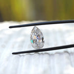 Pear old mine cut moissanite held upright in tweezers