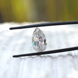 Pear old mine cut moissanite held upright in tweezers