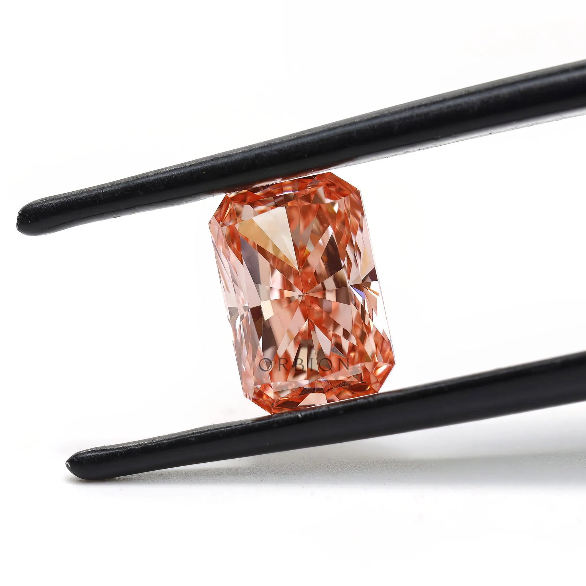 Fancy pink radiant cut lab diamond held in black tweezers
