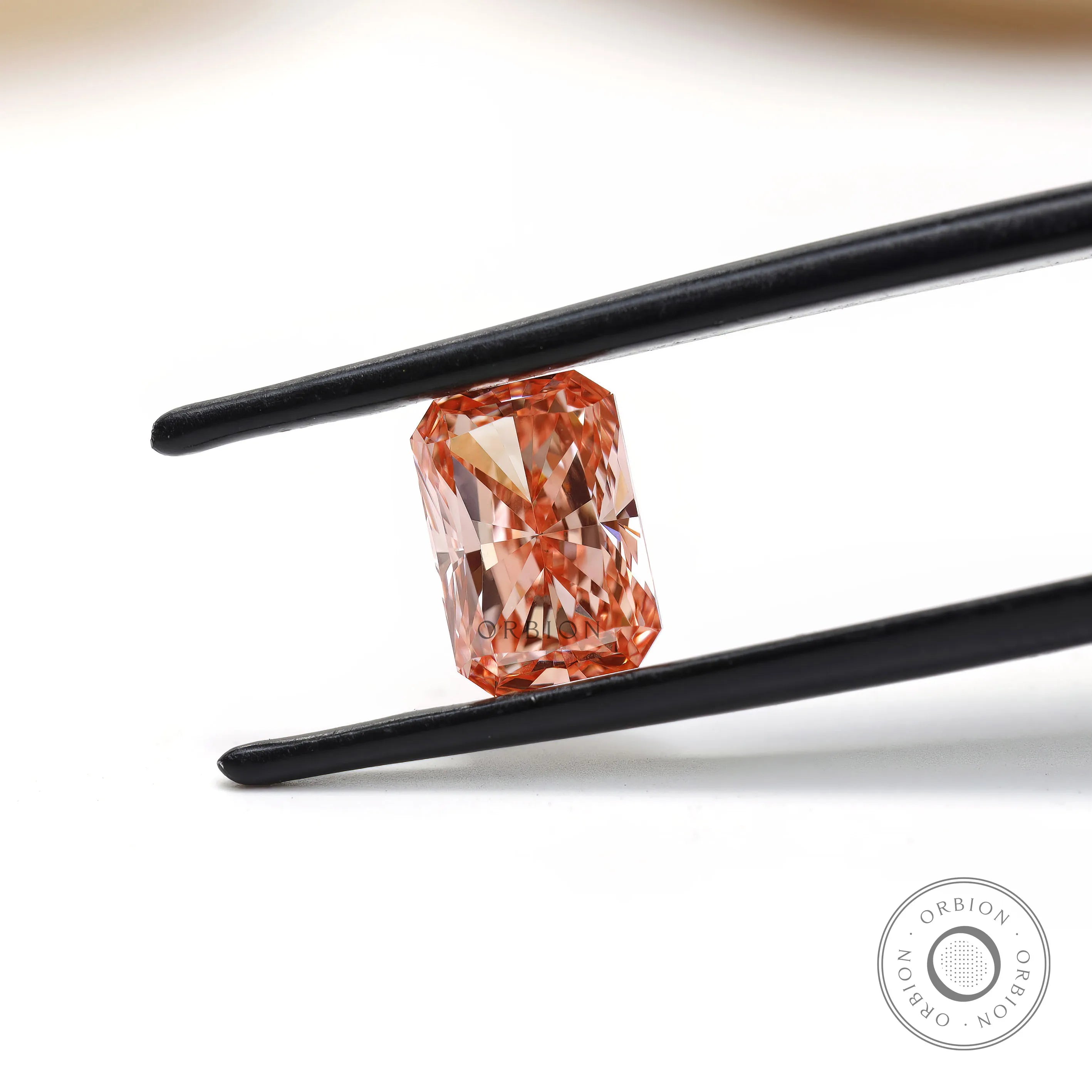 Fancy pink radiant cut lab diamond held in black tweezers