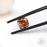 Fancy orange cushion lab diamond held in black tweezers