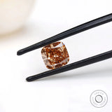 Fancy orange cushion lab diamond held in black tweezers