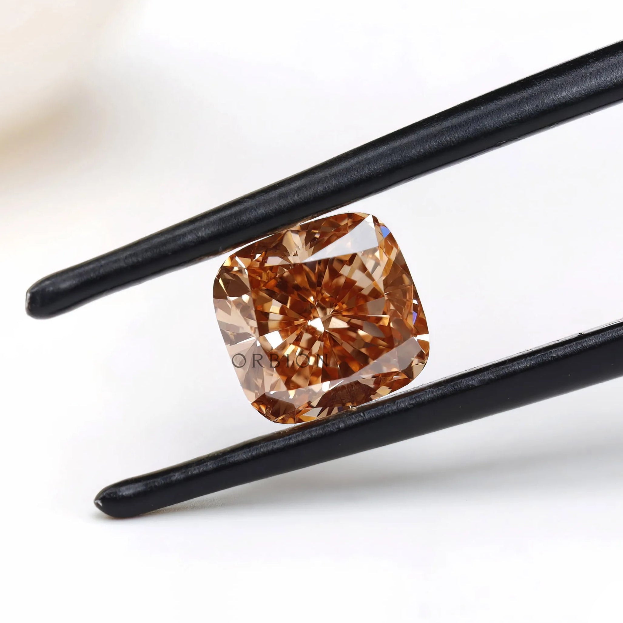 Fancy orange cushion lab diamond held in black tweezers