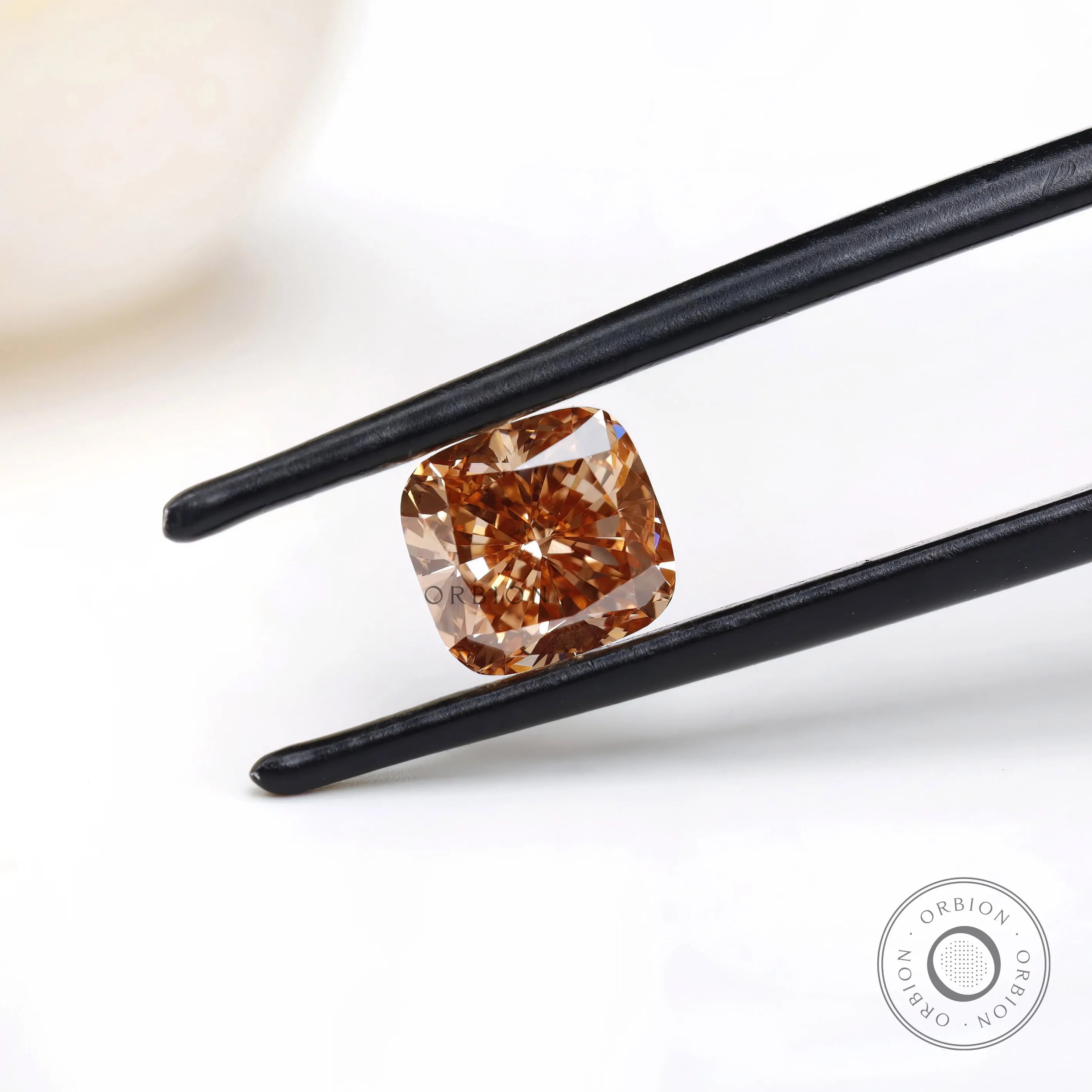 Fancy orange cushion lab diamond held in black tweezers