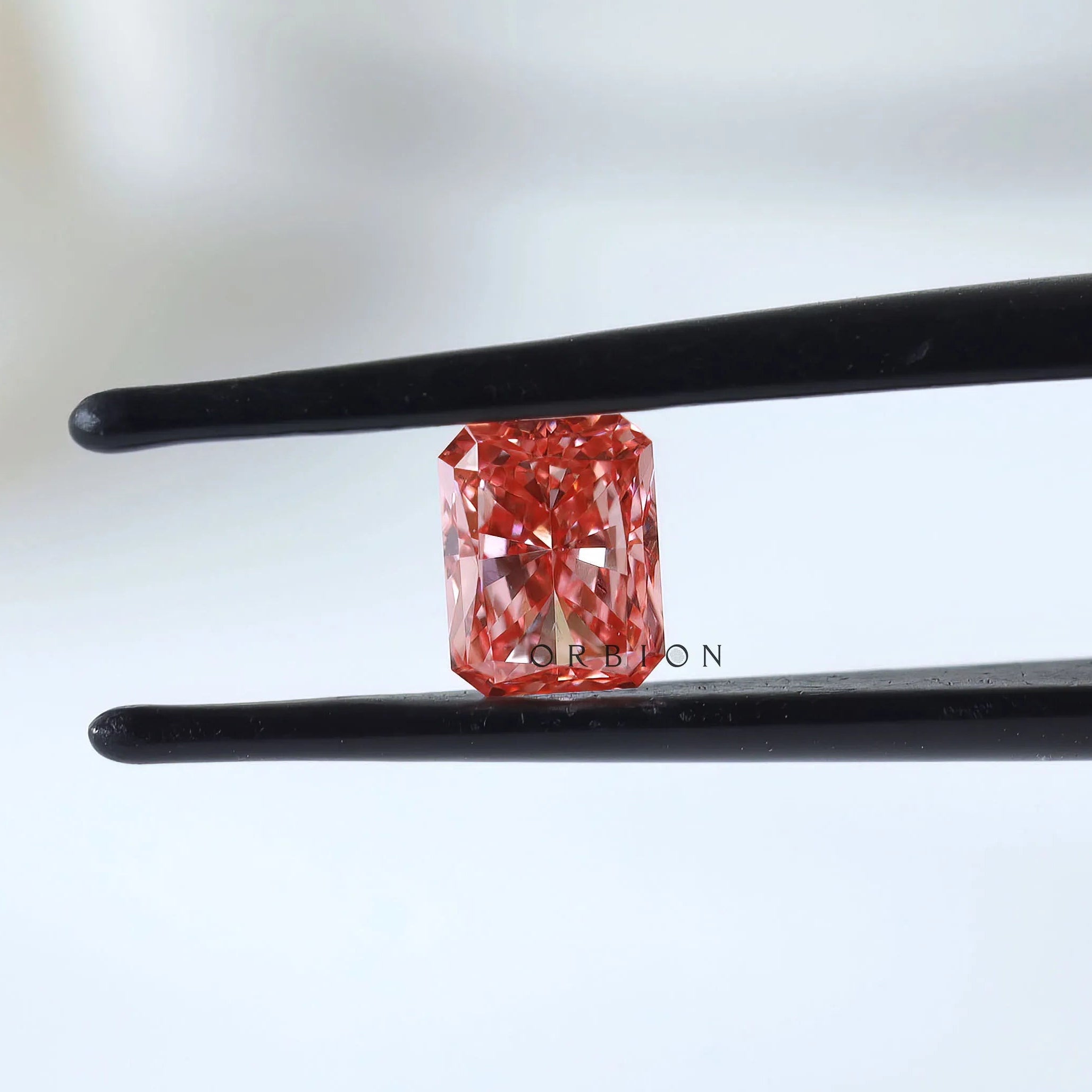 Fancy vivid pink radiant diamond shown in tweezers