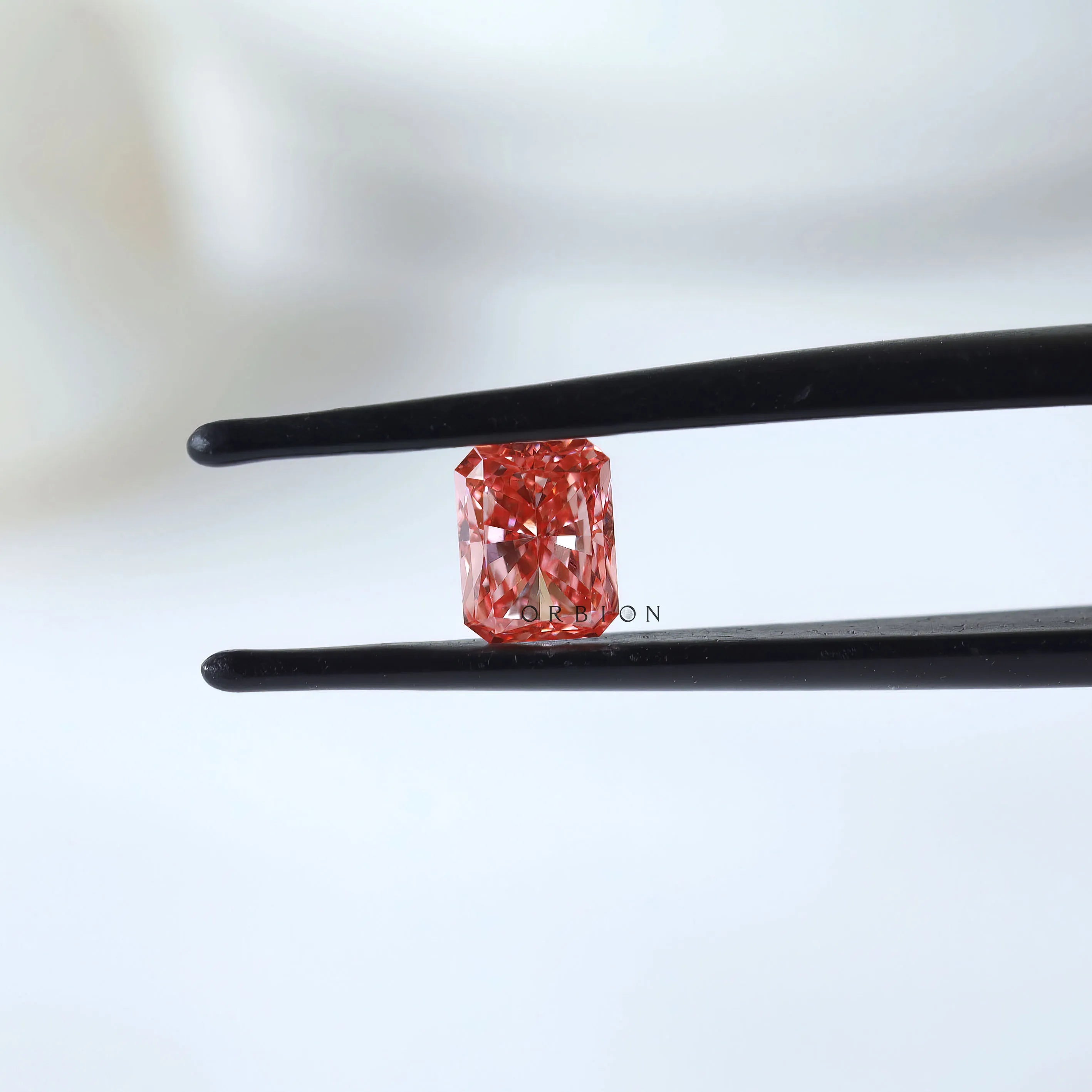 Fancy vivid pink radiant diamond shown in tweezers