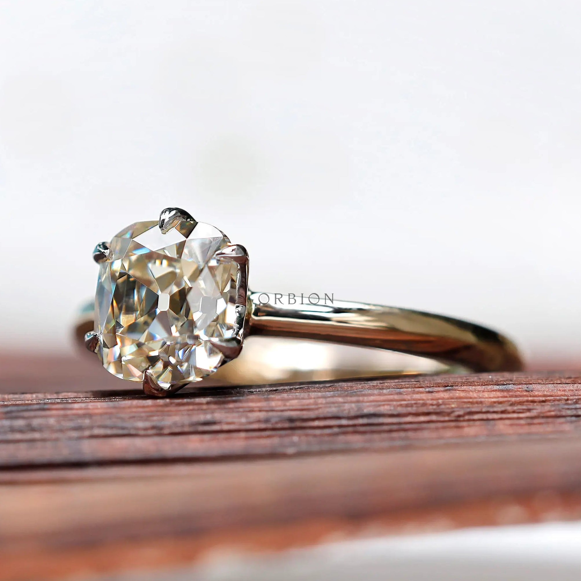 Angled view of off white moissanite engagement ring in two tone gold