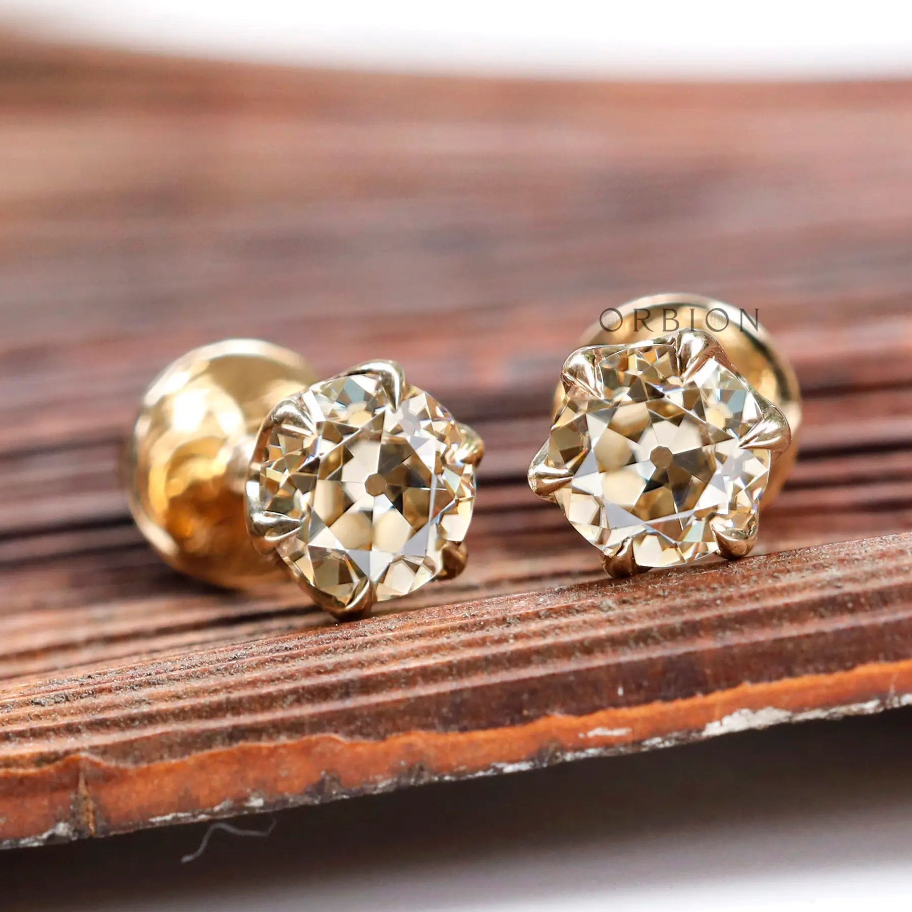 Angled view OEC champagne moissanite stud earrings yellow gold