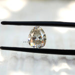 Old Mine Cut Off White Pear Moissanite Loose Stone in tweezers